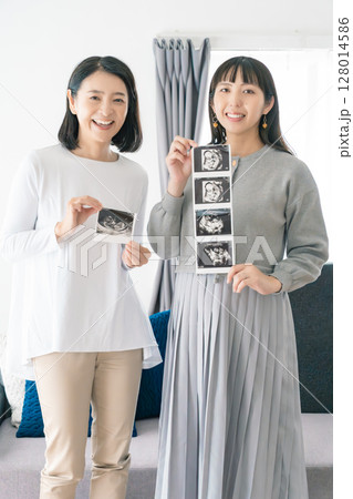 エコー写真を見ながら、赤ちゃんが生まれてくるのが待ち遠しい母と娘 128014586