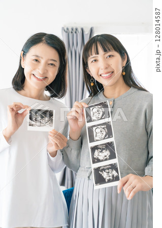 エコー写真を見ながら、赤ちゃんが生まれてくるのが待ち遠しい母と娘 128014587
