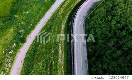 Aerial view of a road in the middle of the forest. Top view of asphalt road through forest with car adventure. Healthy environment road trip travel. Aerial view of a road in the middle of the forest. Top view of asphalt road through forest with car adventure. Healthy environment road trip travel. 128014947