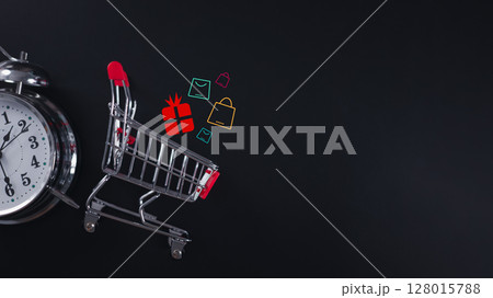 Mini shopping cart with alarm clock and holographic icons for urgent online shopping Mini shopping cart with alarm clock and holographic icons for urgent online shopping 128015788