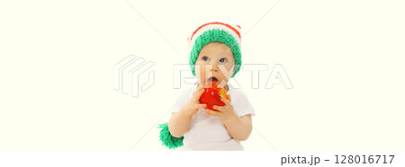 Cute baby eating red apple fruit or playing wearing colorful hat on white studio background Cute baby eating red apple fruit or playing wearing colorful hat on white studio background 128016717
