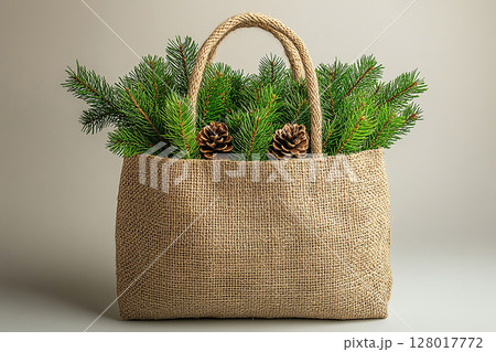 Reusable shopping bag made of fabric with Christmas tree branches on a white background. Reusable shopping bag made of fabric with Christmas tree branches on a white background. 128017772