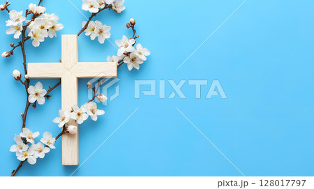 A wooden cross surrounded by delicate blossoms on a vibrant blue background 128017797