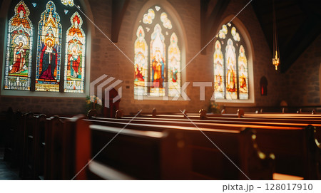 Stained glass windows illuminating a quiet church interior during morning light 128017910