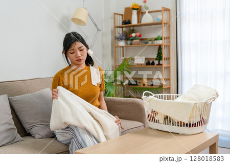 Young modern Asian woman doing house cleaning at home. Confident and independent homemaker maintaining a clean, stylish living space. Young modern Asian woman doing house cleaning at home. Confident and independent homemaker maintaining a clean, stylish living space. 128018583