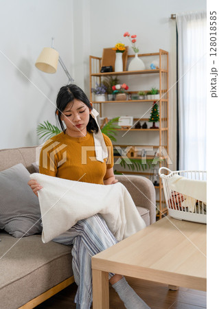 Young modern Asian woman doing house cleaning at home. Confident and independent homemaker maintaining a clean, stylish living space. 128018585