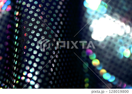 Holographic shiny spots and dots bokeh on fabric for a futuristic disco background Holographic shiny spots and dots bokeh on fabric for a futuristic disco background 128019800