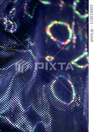 Holographic shiny spots and dots bokeh on fabric for a futuristic disco background Holographic shiny spots and dots bokeh on fabric for a futuristic disco background 128019805