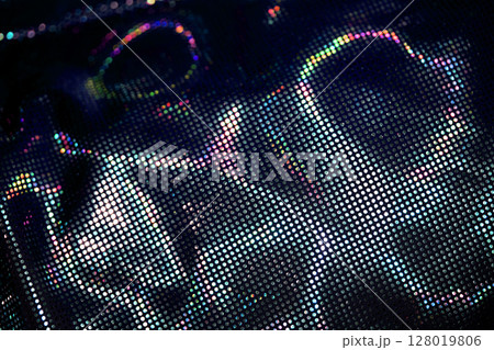 Holographic shiny spots and dots bokeh on fabric for a futuristic disco background Holographic shiny spots and dots bokeh on fabric for a futuristic disco background 128019806