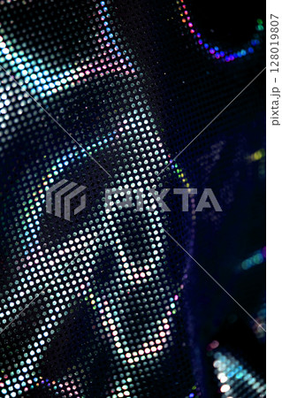 Holographic shiny spots and dots bokeh on fabric for a futuristic disco background Holographic shiny spots and dots bokeh on fabric for a futuristic disco background 128019807
