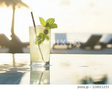 Refreshing cocktail with lime and mint on beach table, sunlit with loungers and sea in background. Refreshing cocktail with lime and mint on beach table, sunlit with loungers and sea in background. 128021251