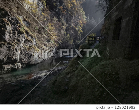 Tranquil mountain stream meanders through rocky gorge in aosta, italy, surrounded by autumn foliage and misty atmosphere under soft sunlight Isollaz waterfall Tranquil mountain stream meanders through rocky gorge in aosta, italy, surrounded by autumn foliage and misty atmosphere under soft sunlight Isollaz waterfall 128021982