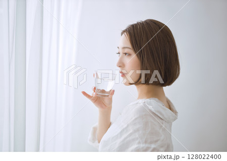 リビングで水を飲む若い女性 128022400