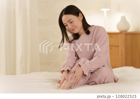 夜ベッドで足のマッサージをする女性 128022523