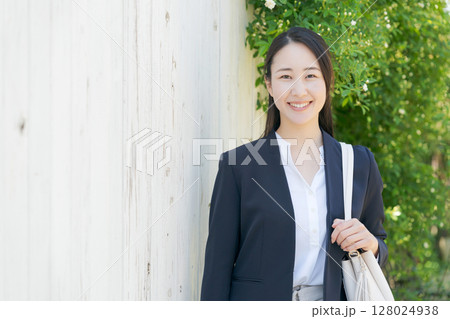 白いフェンスの前に立つスーツの女性 128024938