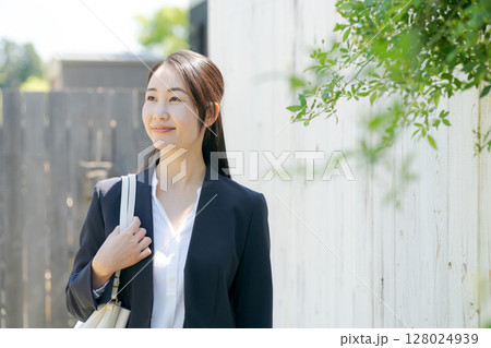 白いフェンスの前に立つスーツの女性 白いフェンスの前に立つスーツの女性 128024939