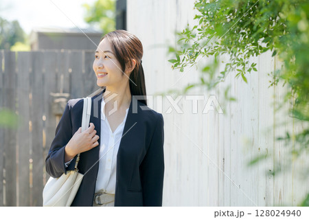 白いフェンスの前に立つスーツの女性 白いフェンスの前に立つスーツの女性 128024940
