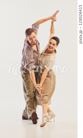 Couple joyfully performing swing dance in vintage attire with energetic and graceful movements Couple joyfully performing swing dance in vintage attire with energetic and graceful movements 128026415