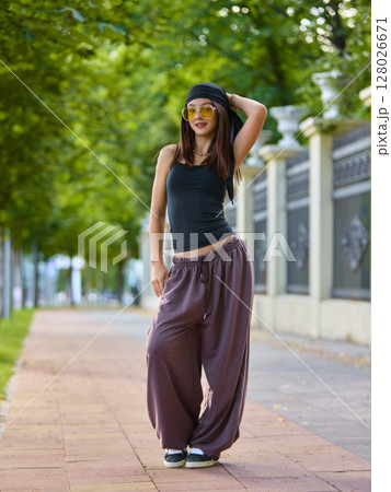 Authentic vibes. Street dancer posing confidently on tree-lined urban sidewalk 128026671