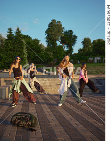 Sound in motion. Group of diverse dancers performing energetic street dance in urban park setting Sound in motion. Group of diverse dancers performing energetic street dance in urban park setting 128026694