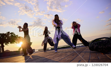 Motion power. Group of young dancers performing on urban street at sunset Motion power. Group of young dancers performing on urban street at sunset 128026704