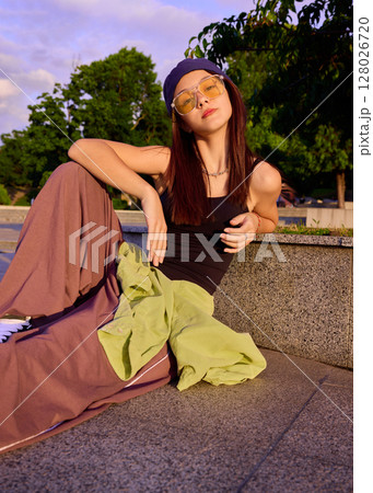 Urban pause. Young woman relaxing outdoors in casual street dance attire 128026720