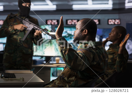 Dangerous terrorist threatening soldiers with rifles after hijacking their base of operations. Outlaw using gun to control kidnapped hostages during guerilla warfare armed conflict 128026721