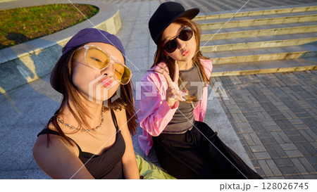 Youthful dancers posing playfully in urban setting with vibrant casual streetwear and accessories Youthful dancers posing playfully in urban setting with vibrant casual streetwear and accessories 128026745