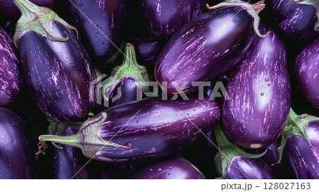 A grouping of deep purple eggplants their glossy skins reflecting the soft light and showcasing their plump rounded shape A grouping of deep purple eggplants their glossy skins reflecting the soft light and showcasing their plump rounded shape 128027163