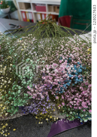 A vibrant assortment of multicolored gypsophila flowers laid out on a florists table, with tools in the background. Floral design, color coordination A vibrant assortment of multicolored gypsophila flowers laid out on a florists table, with tools in the background. Floral design, color coordination 128027683