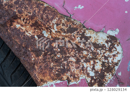 Close-up texture of heavy rust on peeling pink painted metal surface Close-up texture of heavy rust on peeling pink painted metal surface 128029134