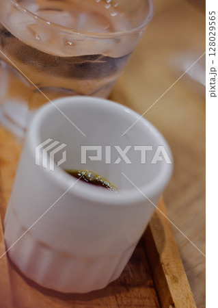 Close-up of a small white cup with espresso coffee and a glass of ice water Close-up of a small white cup with espresso coffee and a glass of ice water 128029565