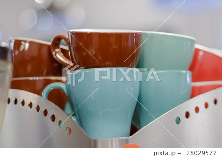 Stacked colorful ceramic cups in a metal holder, close up view Stacked colorful ceramic cups in a metal holder, close up view 128029577