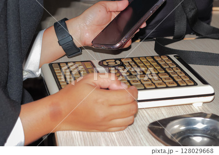 Person Holding Smartphone While Using Vintage Style Mechanical Keyboard Person Holding Smartphone While Using Vintage Style Mechanical Keyboard 128029668
