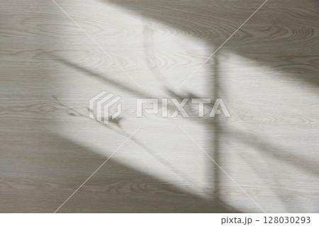 Wood texture background with natural shadows and silhouettes of leaves from natural light streaming through a window. Wood texture background with natural shadows and silhouettes of leaves from natural light streaming through a window. 128030293
