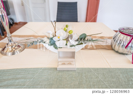 Elegant gold wedding rings lie among soft satin white ribbon. Front vertical view. Mockup for wedding postcard 128036963