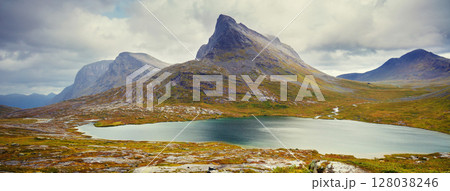 Mountain landscape. Rocky shore of a mountain lake on a rainy autumn morning. Beautiful nature of Norway. Horizontal banner 128038246
