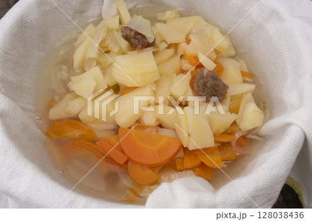 野菜コンソメスープを作る工程　煮込んだ野菜を漉してスープをとる 128038436