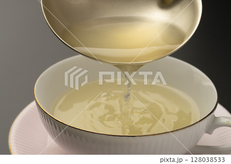 野菜コンソメスープをおたまでスープカップに盛り付ける 128038533