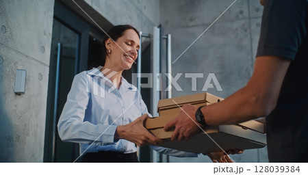 Man Working in Pizza Delivery Service, Brining Restaurant Food for Businesswoman Working in Office 128039384