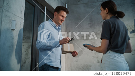 Man Taking Package from Female Postal Worker, Paying Contactless Using Smartphone 128039475