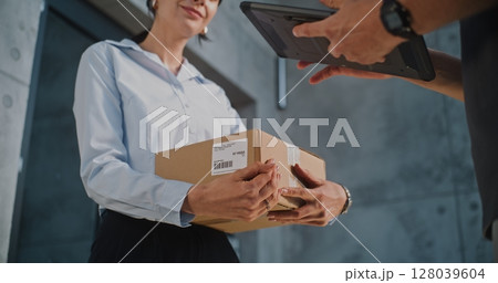Close Up of Postman Delivering Parcel Box to Addressee, Getting Client's Signature on Digital Tablet Close Up of Postman Delivering Parcel Box to Addressee, Getting Client's Signature on Digital Tablet 128039604