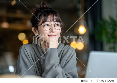 笑顔でパソコン作業する眼鏡の若い女性ポートレート 128041226