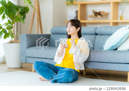 部屋でスマホを操作する若い女性 128042686