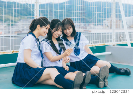 屋上でスマホを見る女子高生 128042824