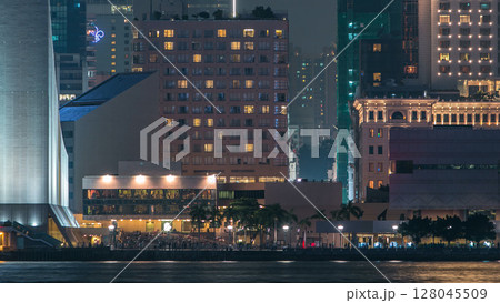 People sitting on the stairs near Hong Kong Cultural Centre with palms and towers on background timelapse. People sitting on the stairs near Hong Kong Cultural Centre with palms and towers on background timelapse. 128045509
