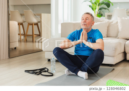 Yoga mindfulness meditation. Senior adult mature man practicing yoga at home. Mid age old grandfather sitting in lotus pose on yoga mat meditating relaxing. Older man doing breathing practice 128046802