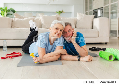 Fitness workout home training. Senior adult mature healthy fit couple resting after sports exercise on yoga mat at home. Mid age old husband wife have training workout. Health care healthy lifestyle Fitness workout home training. Senior adult mature healthy fit couple resting after sports exercise on yoga mat at home. Mid age old husband wife have training workout. Health care healthy lifestyle 128046804