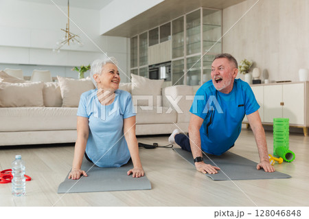Fitness workout training. Senior adult mature healthy fit couple doing sports exercise on yoga mat on floor at home. Mid age old husband wife have training workout. Health care healthy lifestyle 128046848