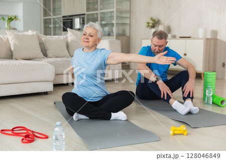 Fitness workout training. Senior adult mature healthy fit couple doing sports exercise on yoga mat on floor at home. Mid age old husband wife have training workout. Health care healthy lifestyle 128046849